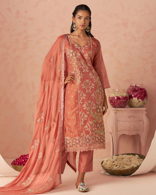 Woman in a traditional pink embroidered outfit with a matching dupatta against a pink background.