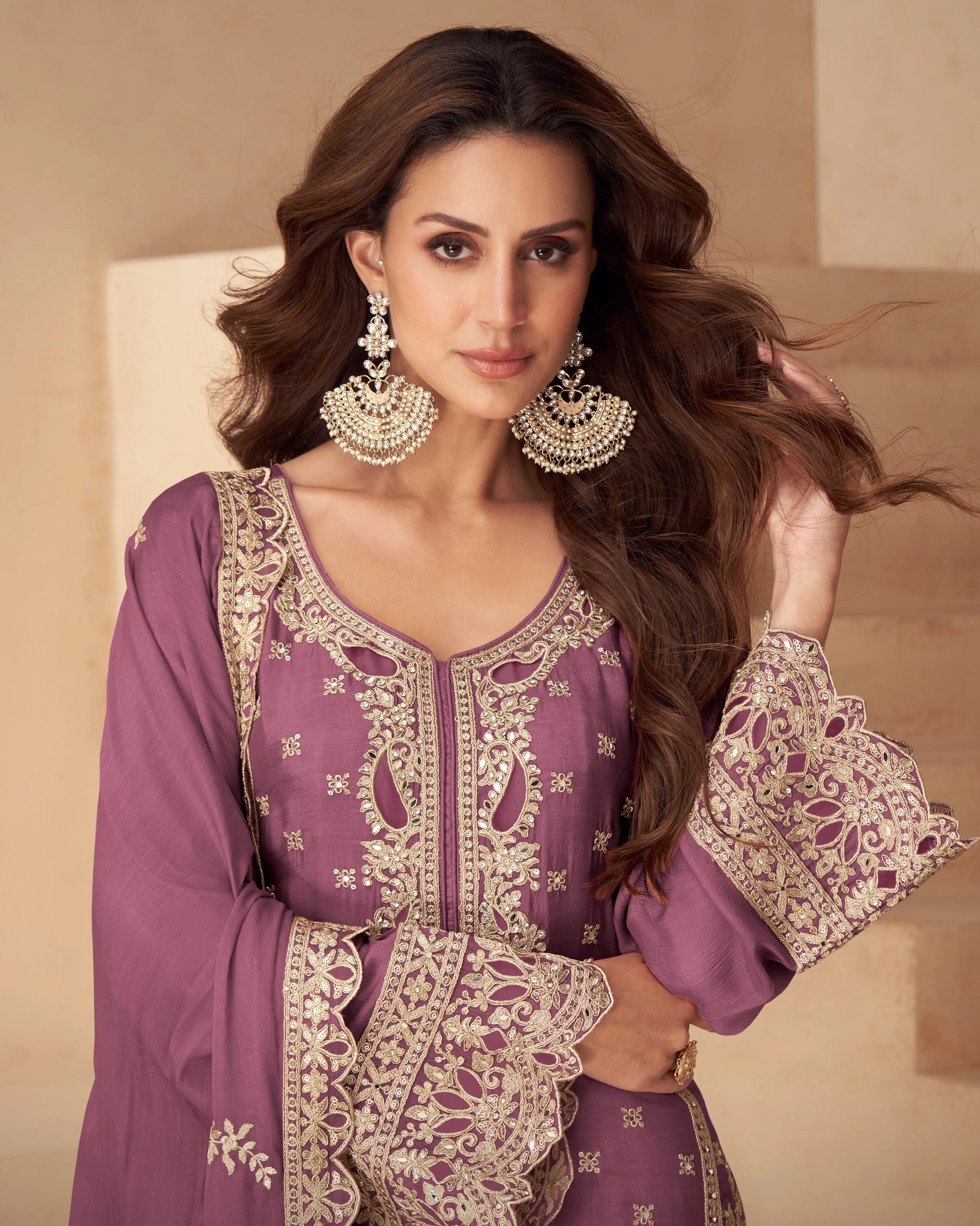 Woman wearing a purple embroidered outfit with gold details against a beige background