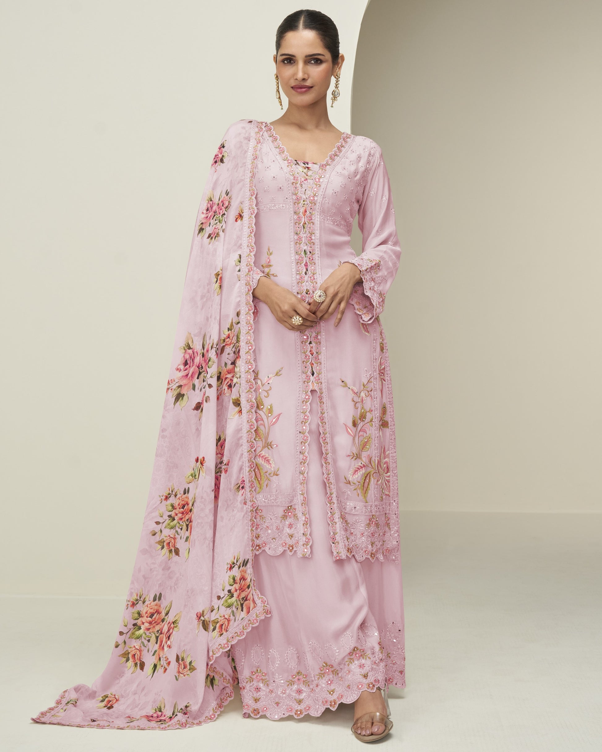 Woman wearing a pink floral dress with a matching dupatta on a plain background