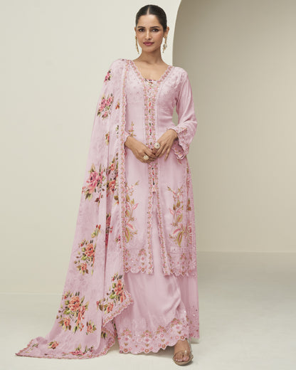 Woman wearing a pink floral dress with a matching dupatta on a plain background