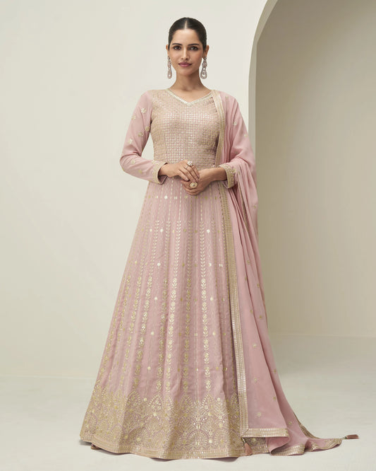 Woman wearing a pink and gold traditional outfit with a plain background