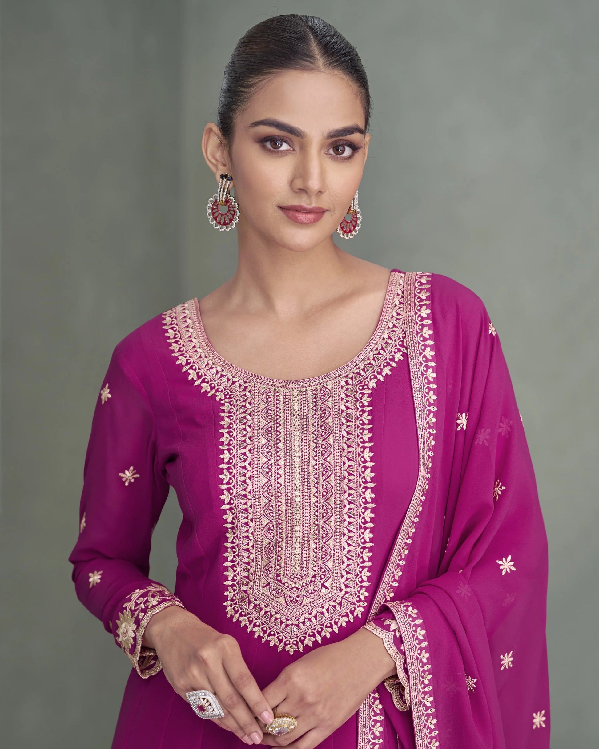 Woman wearing a vibrant purple traditional outfit with intricate embroidery on a gray background