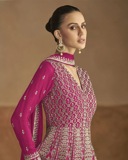 Woman wearing a pink and white patterned traditional outfit against a brown background