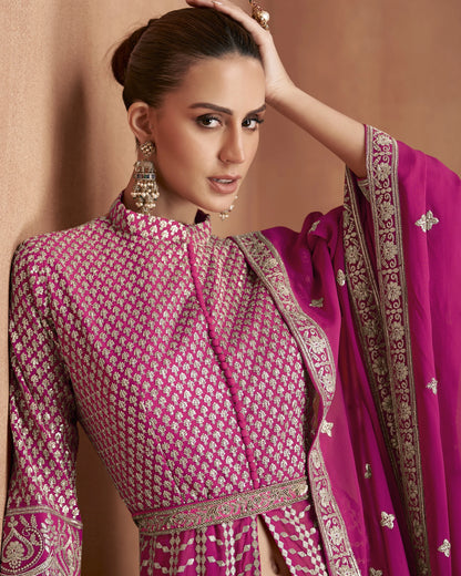 Woman wearing a traditional pink and gold outfit with a matching dupatta against a beige background
