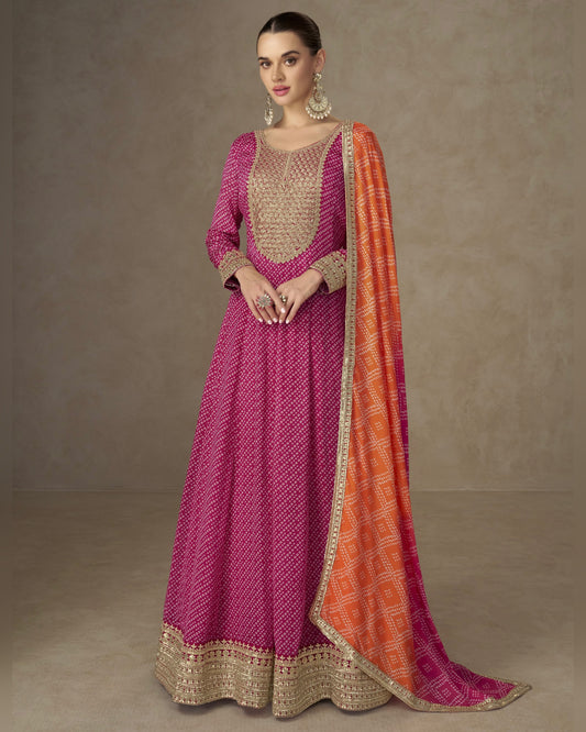 Woman wearing a pink and orange traditional outfit with a matching shawl on a neutral background