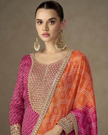 Woman wearing a traditional outfit with pink and orange colors and gold embroidery.