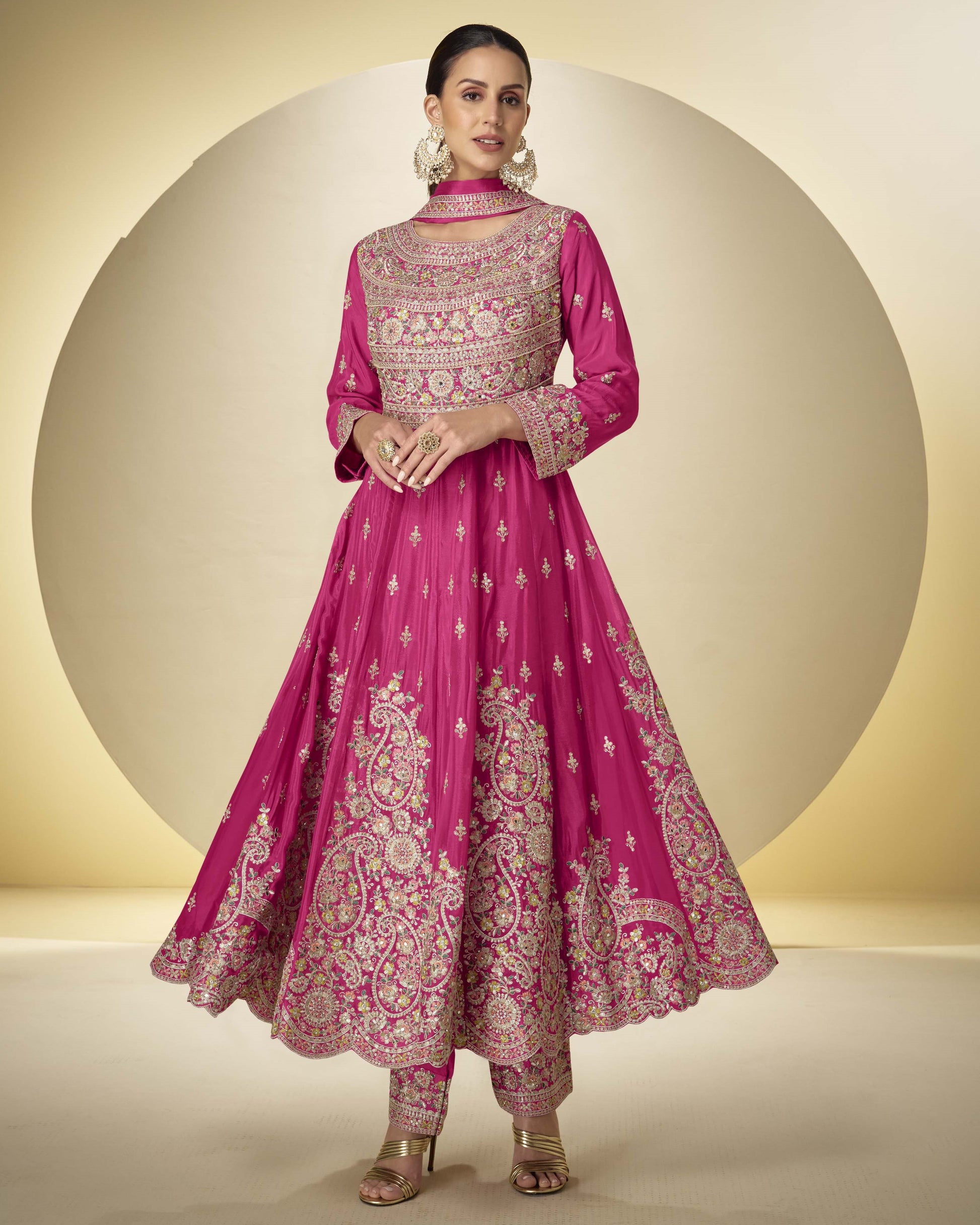 Woman wearing a pink embroidered traditional outfit against a beige background