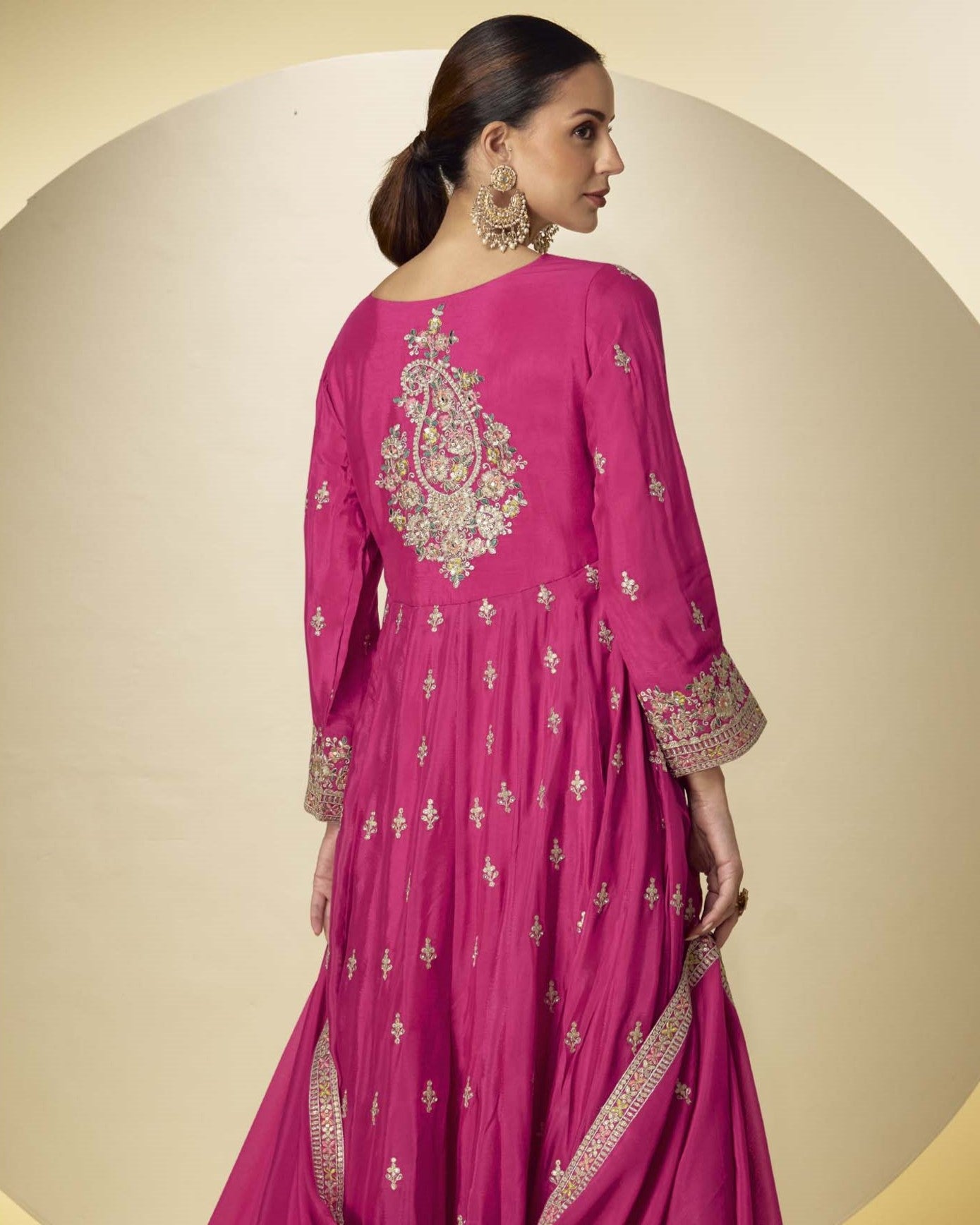 Woman wearing a pink embroidered traditional outfit on a beige background