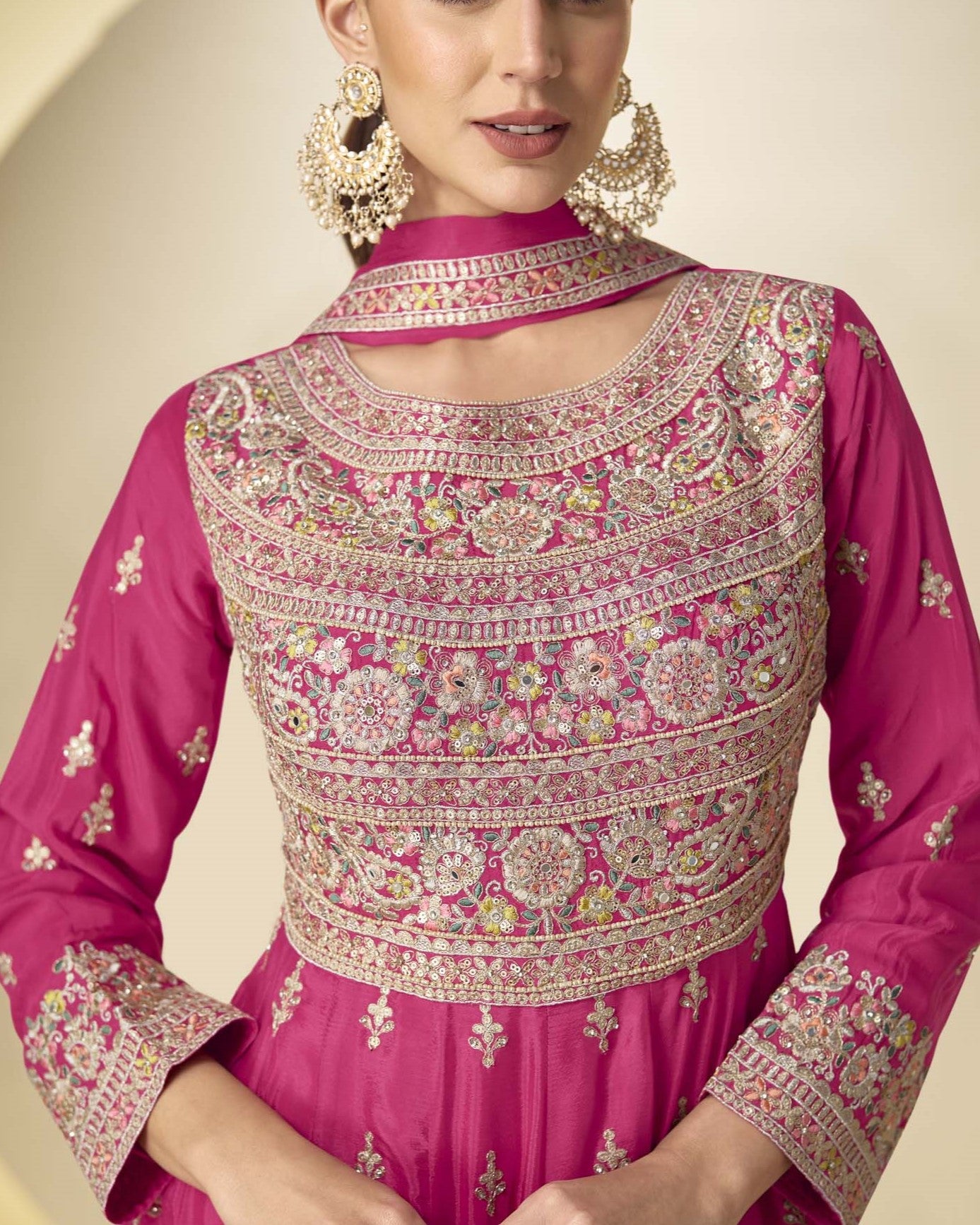 Pink embroidered traditional outfit with intricate patterns on a neutral background