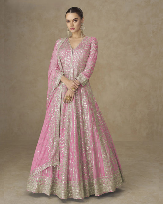 Woman wearing a pink and gold traditional outfit on a beige background