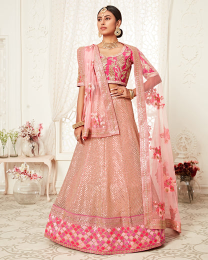 Woman wearing a traditional pink and beige outfit with floral patterns in a decorated room.