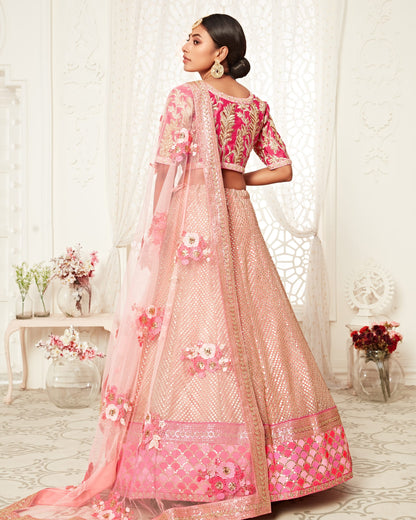 Woman wearing a traditional pink and beige embroidered outfit in a decorated room.