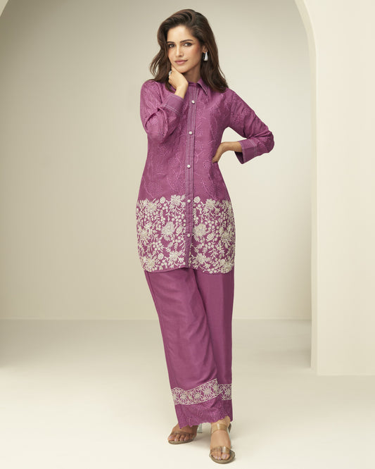 Woman wearing a purple traditional outfit with floral embroidery on a white background