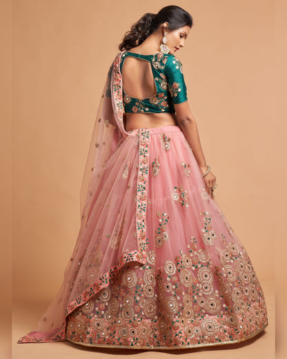 Woman wearing a traditional pink and green embroidered outfit on a beige background