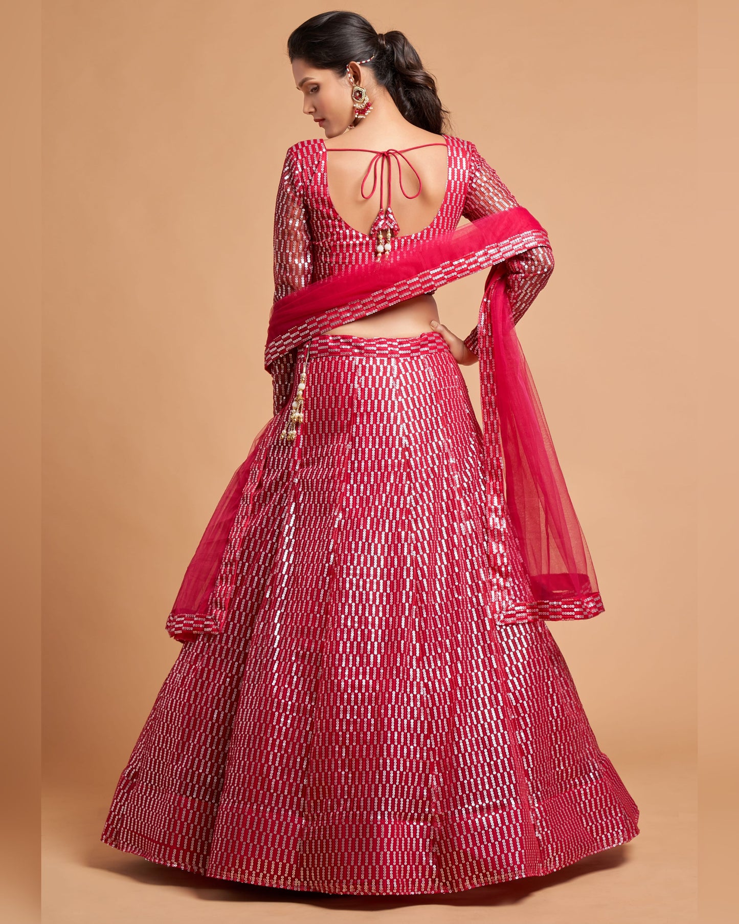 Red and white patterned traditional outfit with a sheer red dupatta on a beige background