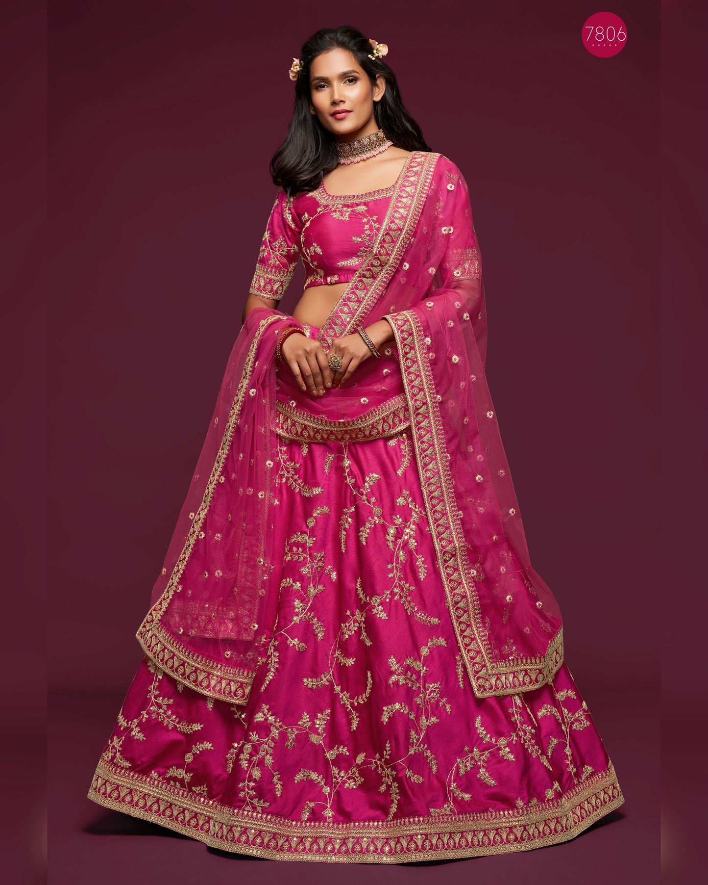 Woman wearing a traditional pink embroidered lehenga on a purple background