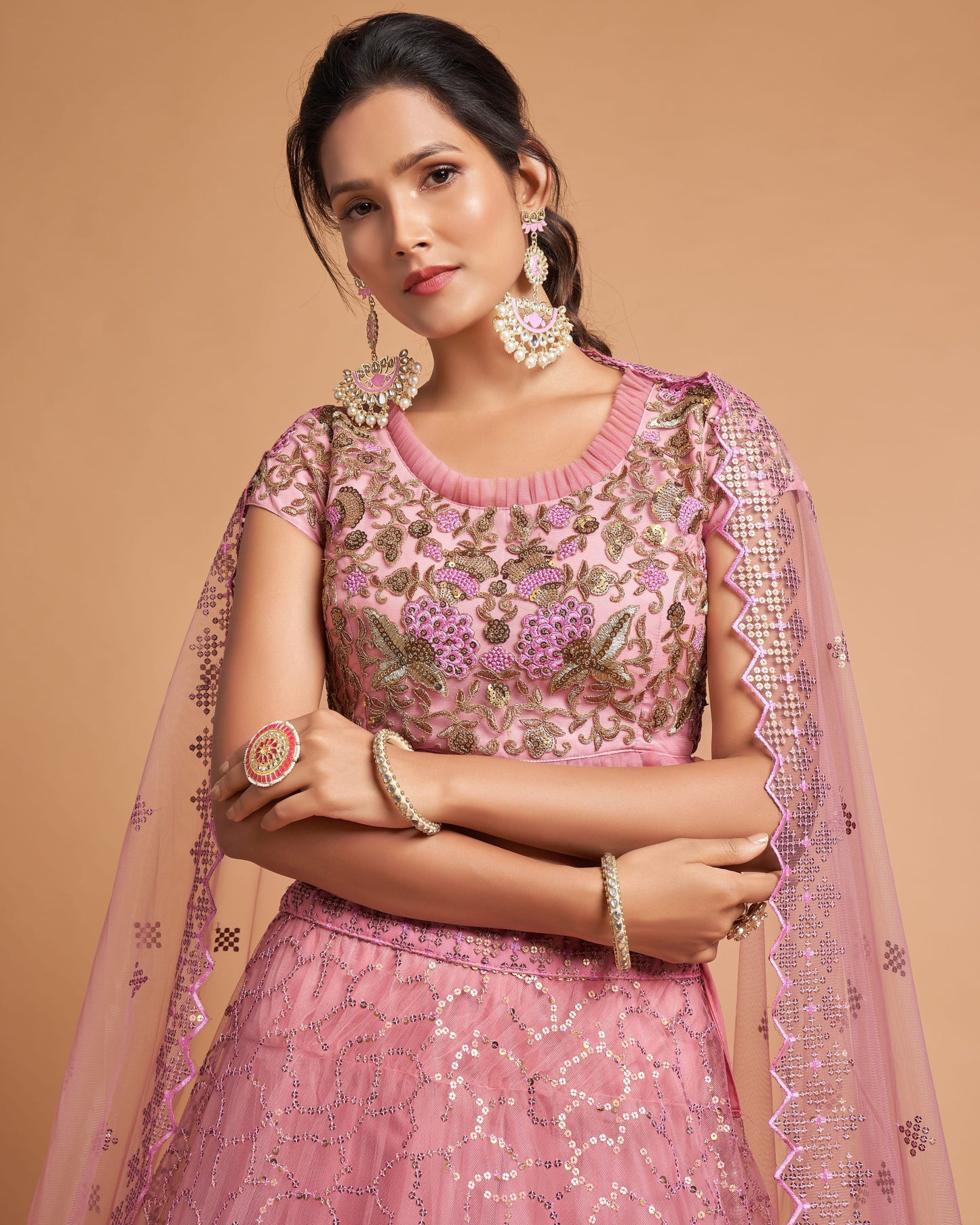 Woman wearing a pink embroidered traditional outfit with a beige background
