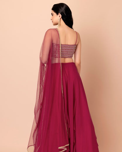 Woman wearing a red saree with a patterned blouse on a beige background