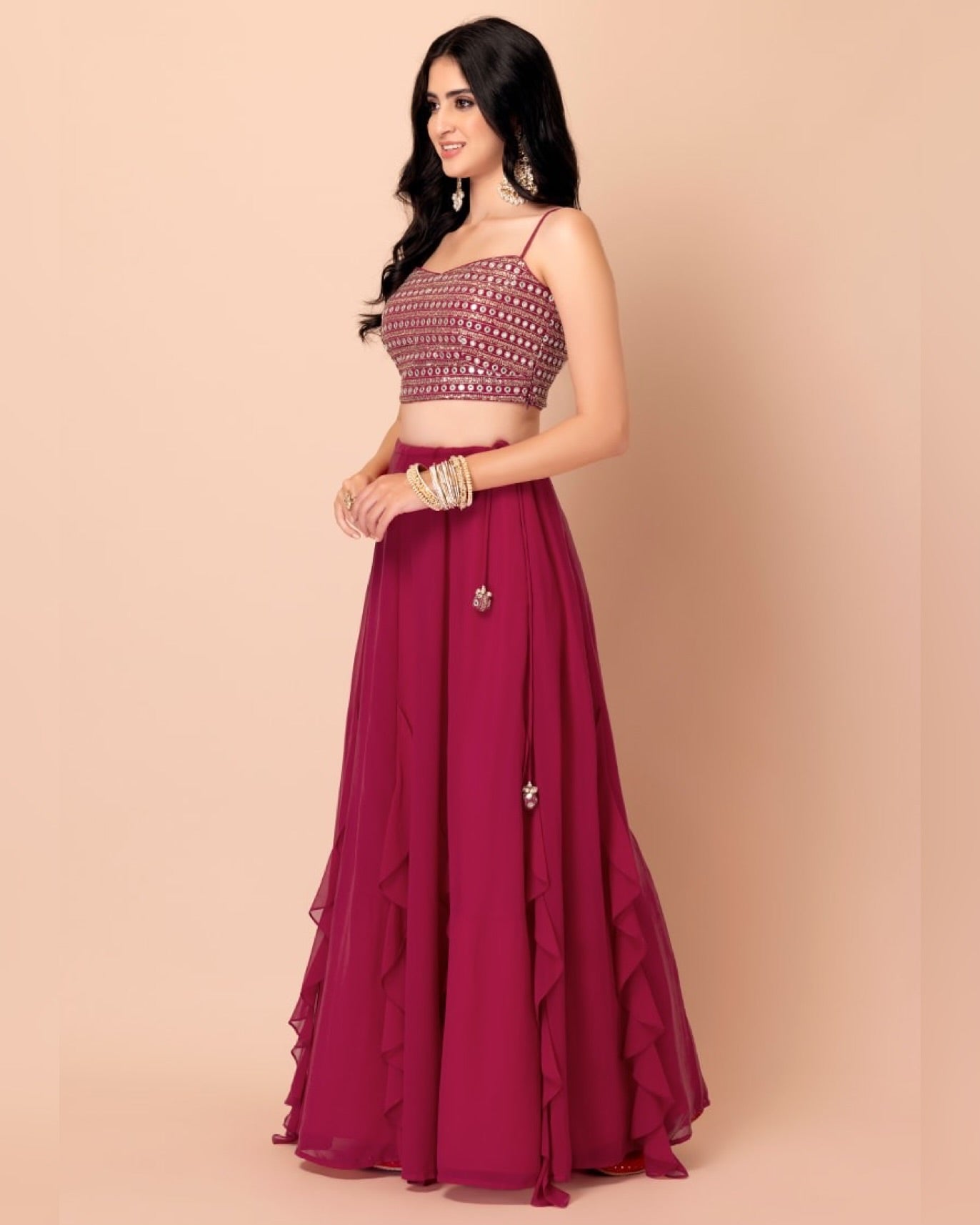 Woman wearing a maroon and pink traditional outfit on a beige background