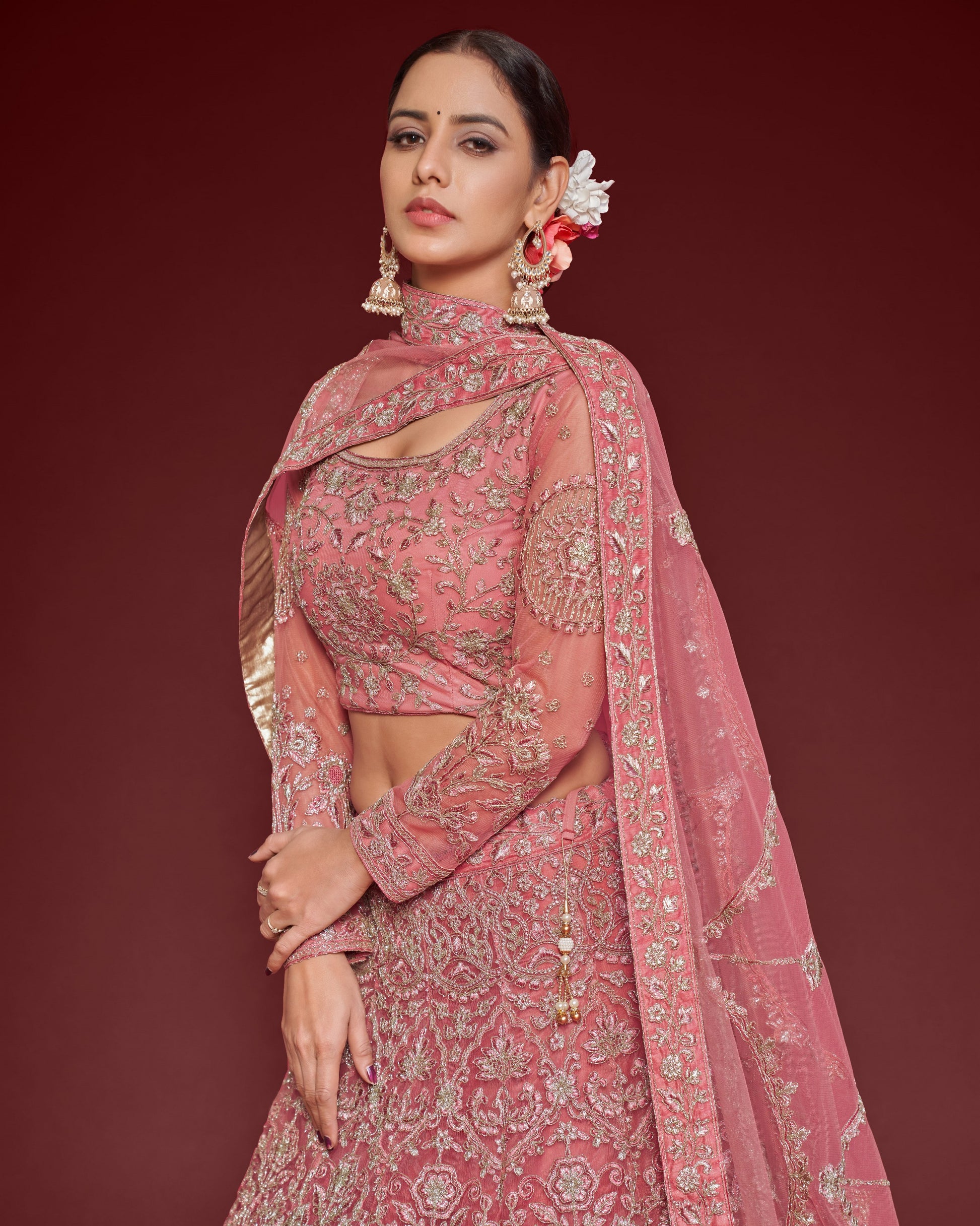 Woman in a pink traditional outfit with intricate designs on a red background