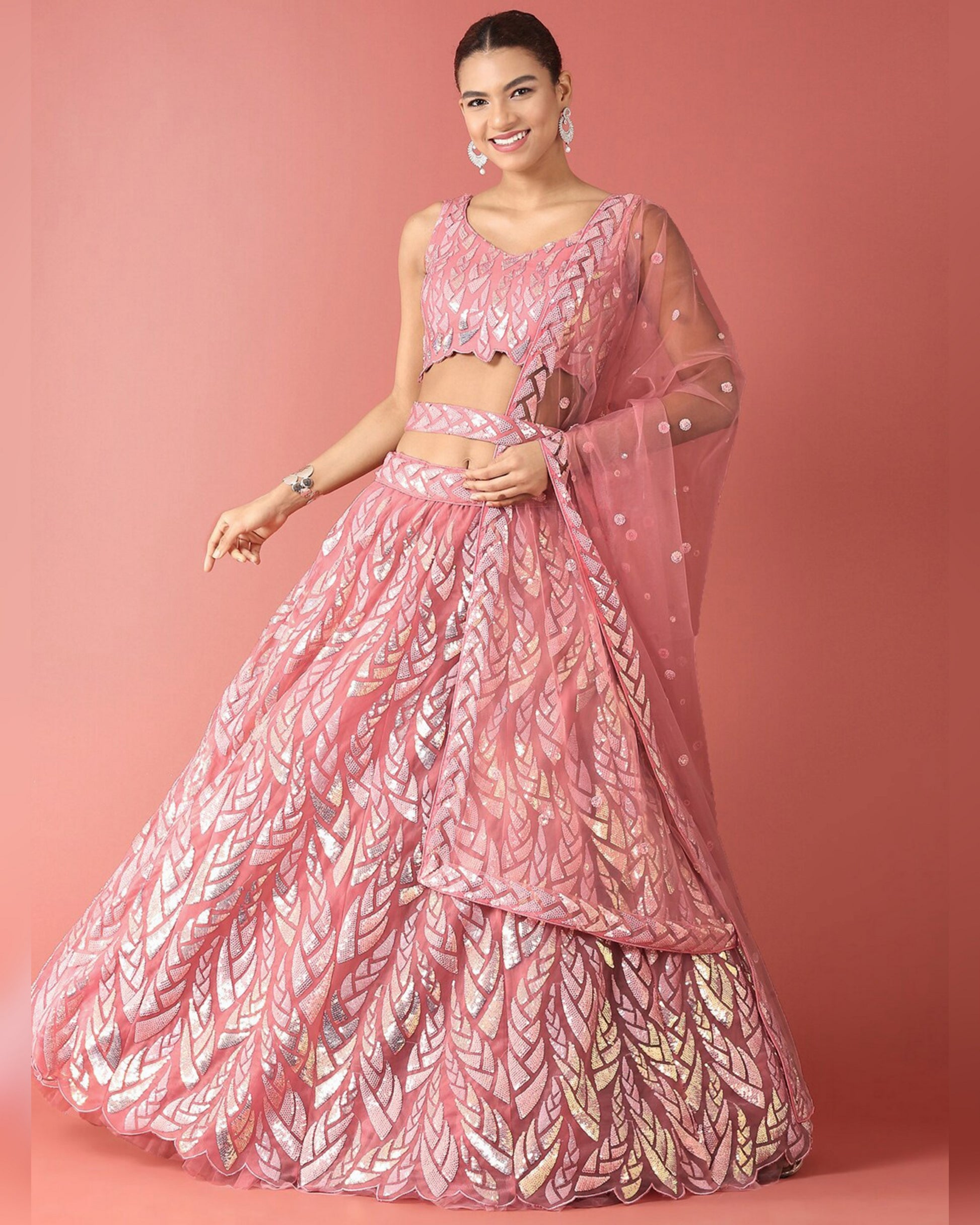 Woman wearing a pink and white patterned lehenga on a pink background
