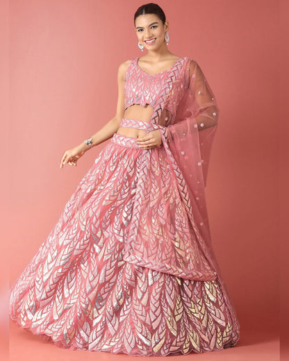 Woman wearing a pink and white patterned lehenga on a pink background