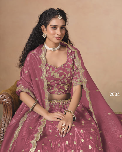 Woman in a traditional pink and gold outfit with jewelry against a beige background
