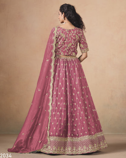 Woman wearing a pink embroidered traditional outfit with a matching shawl on a beige background