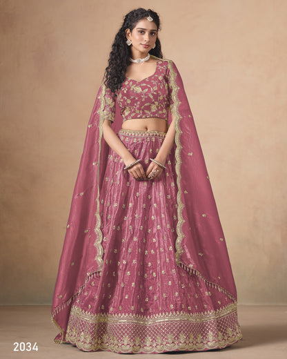 Woman wearing a traditional pink and gold embroidered lehenga on a beige background