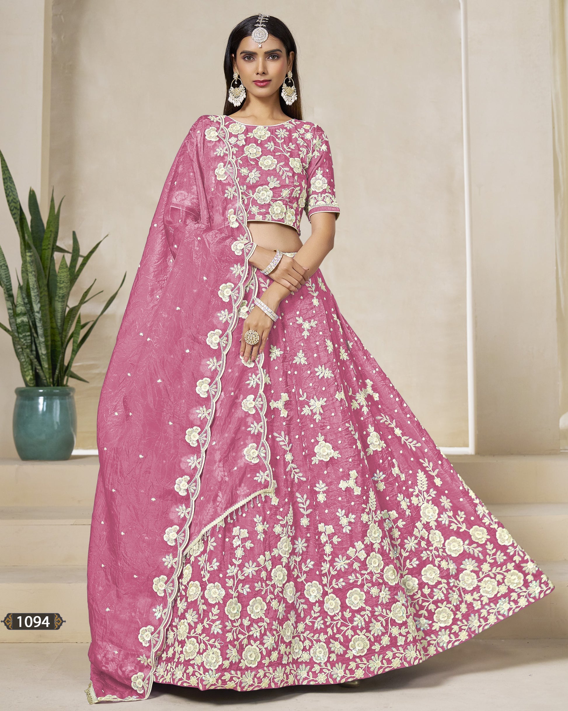 Woman wearing a pink floral saree with a matching blouse in an indoor setting.
