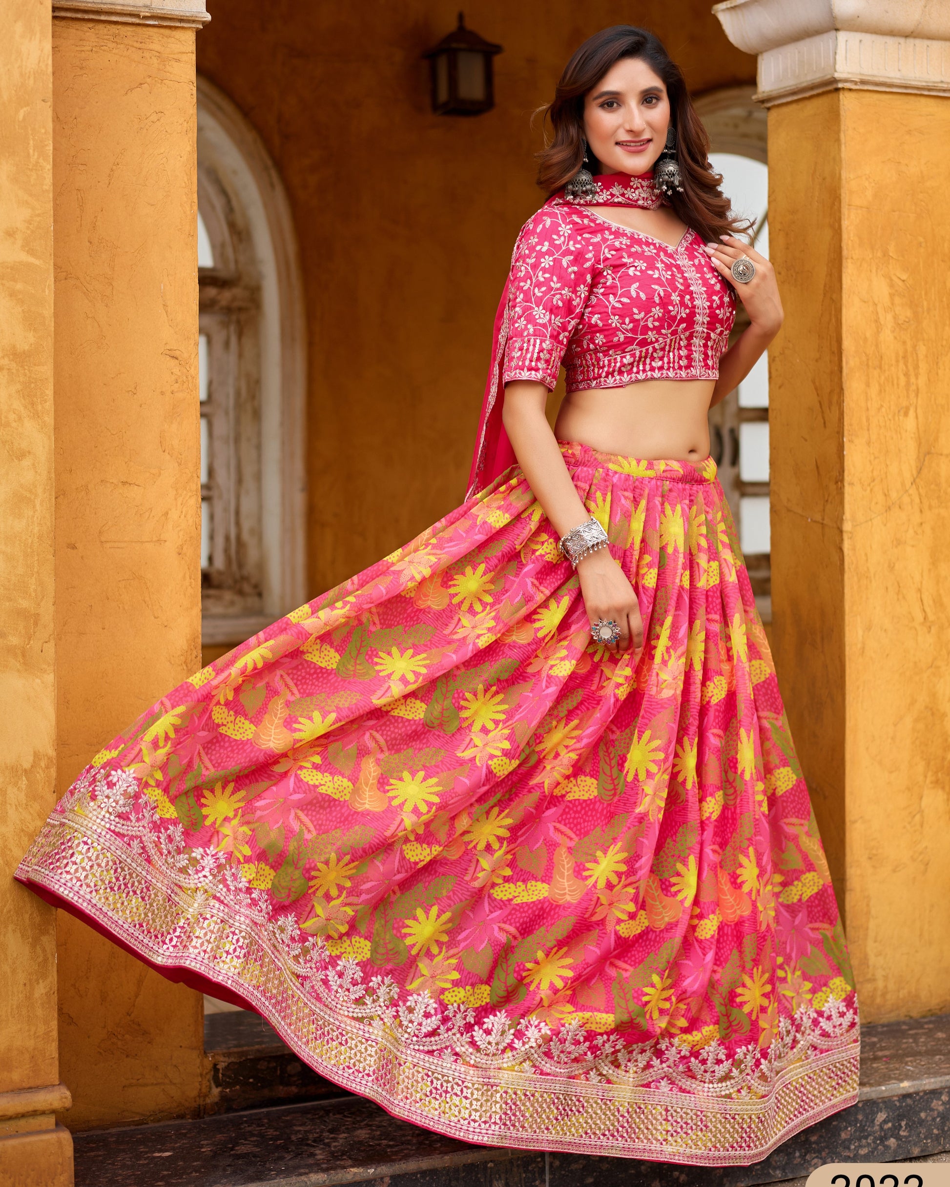 Woman wearing a pink and yellow traditional outfit in front of a yellow wall.