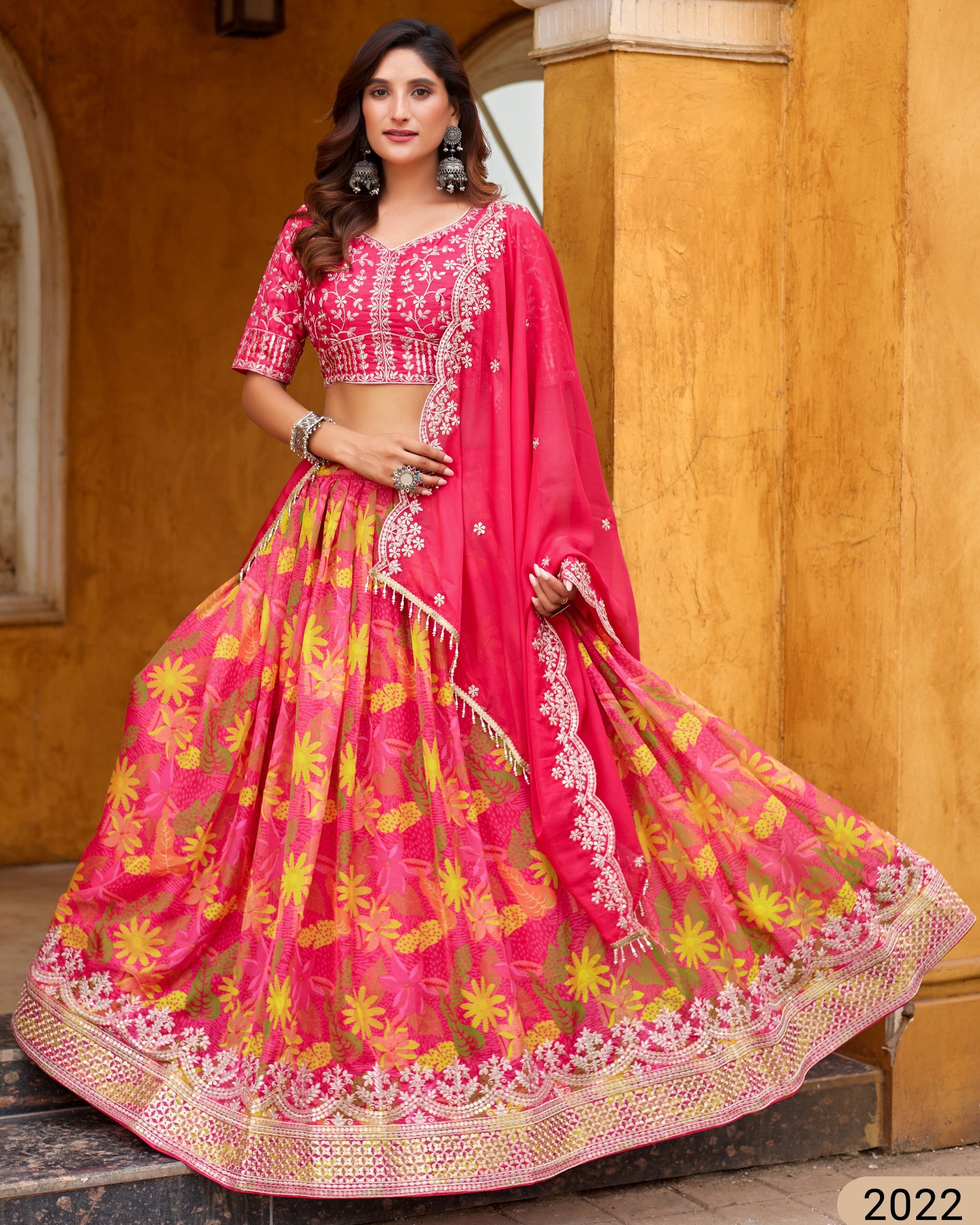 Woman wearing a pink and yellow traditional outfit with a floral pattern.