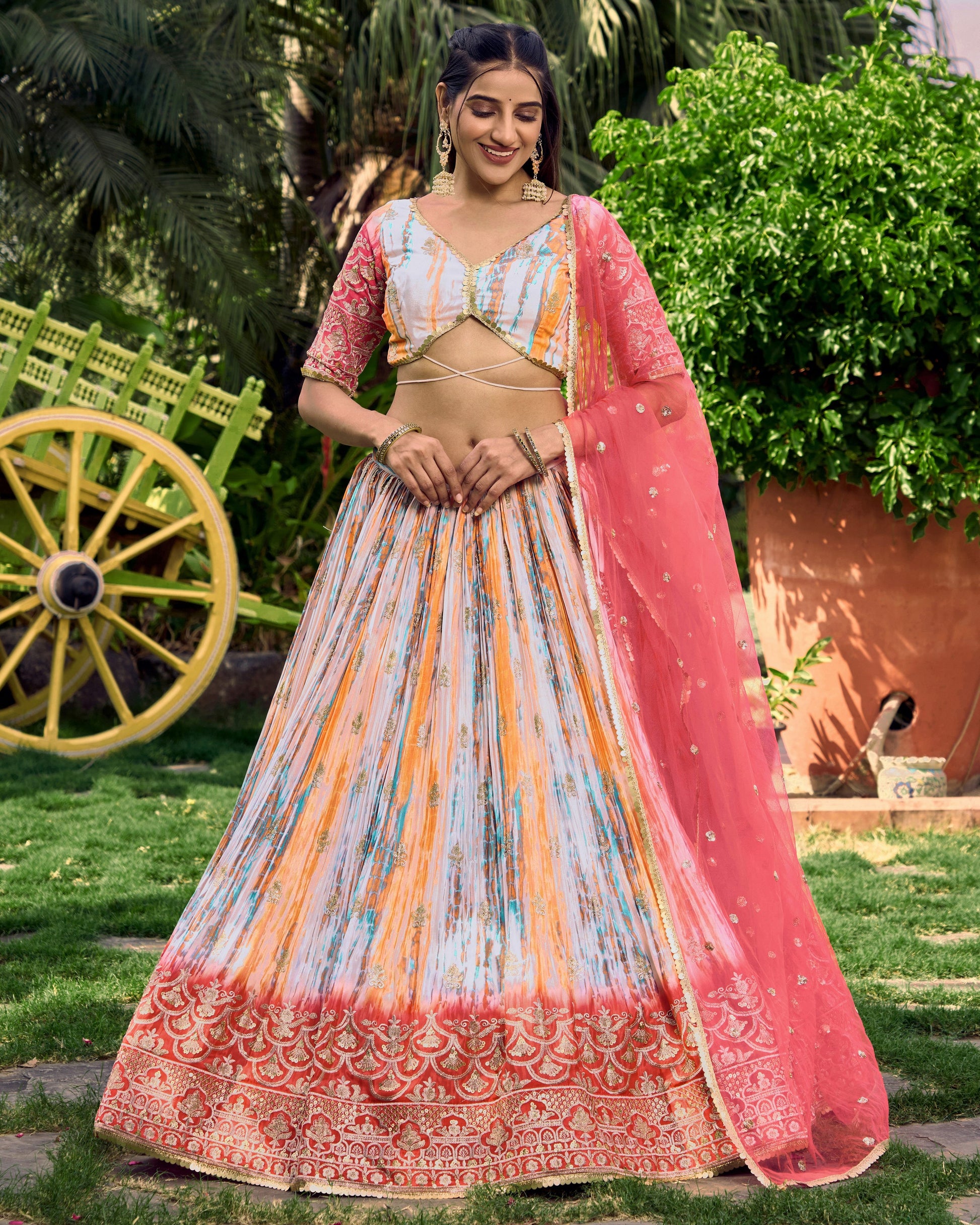 Woman in traditional outfit with a pink dupatta standing outdoors.