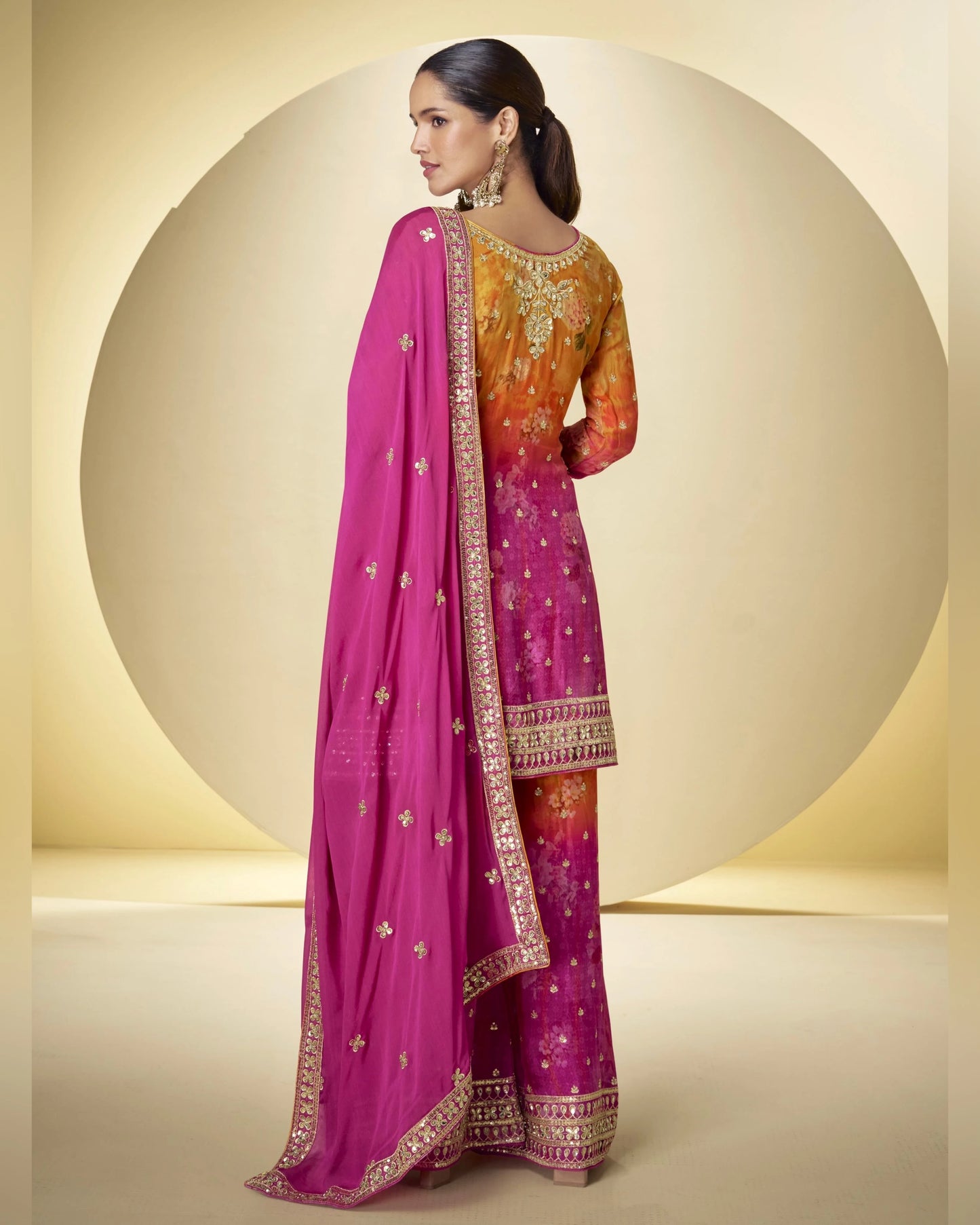 Woman wearing a traditional outfit with a pink and orange saree on a beige background