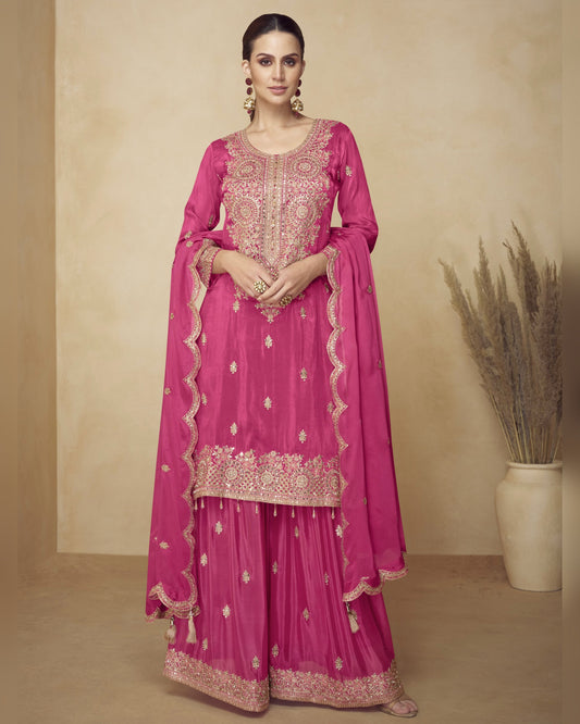 Pink traditional outfit with intricate embroidery on a beige background