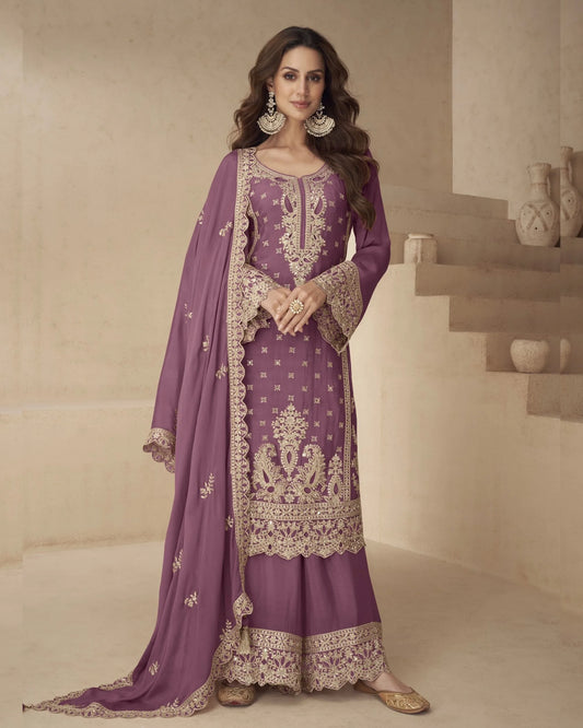 Woman wearing a purple embroidered traditional outfit in a neutral setting