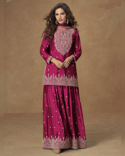 Woman wearing a pink traditional outfit with intricate embroidery on a brown background