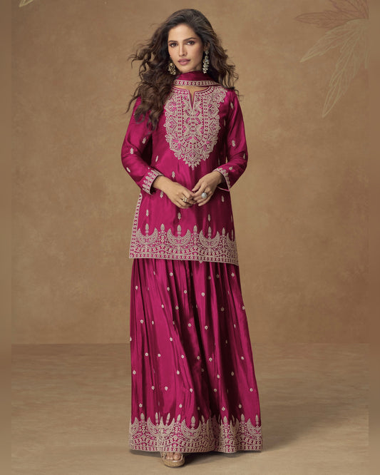 Woman wearing a pink traditional outfit with intricate embroidery on a brown background