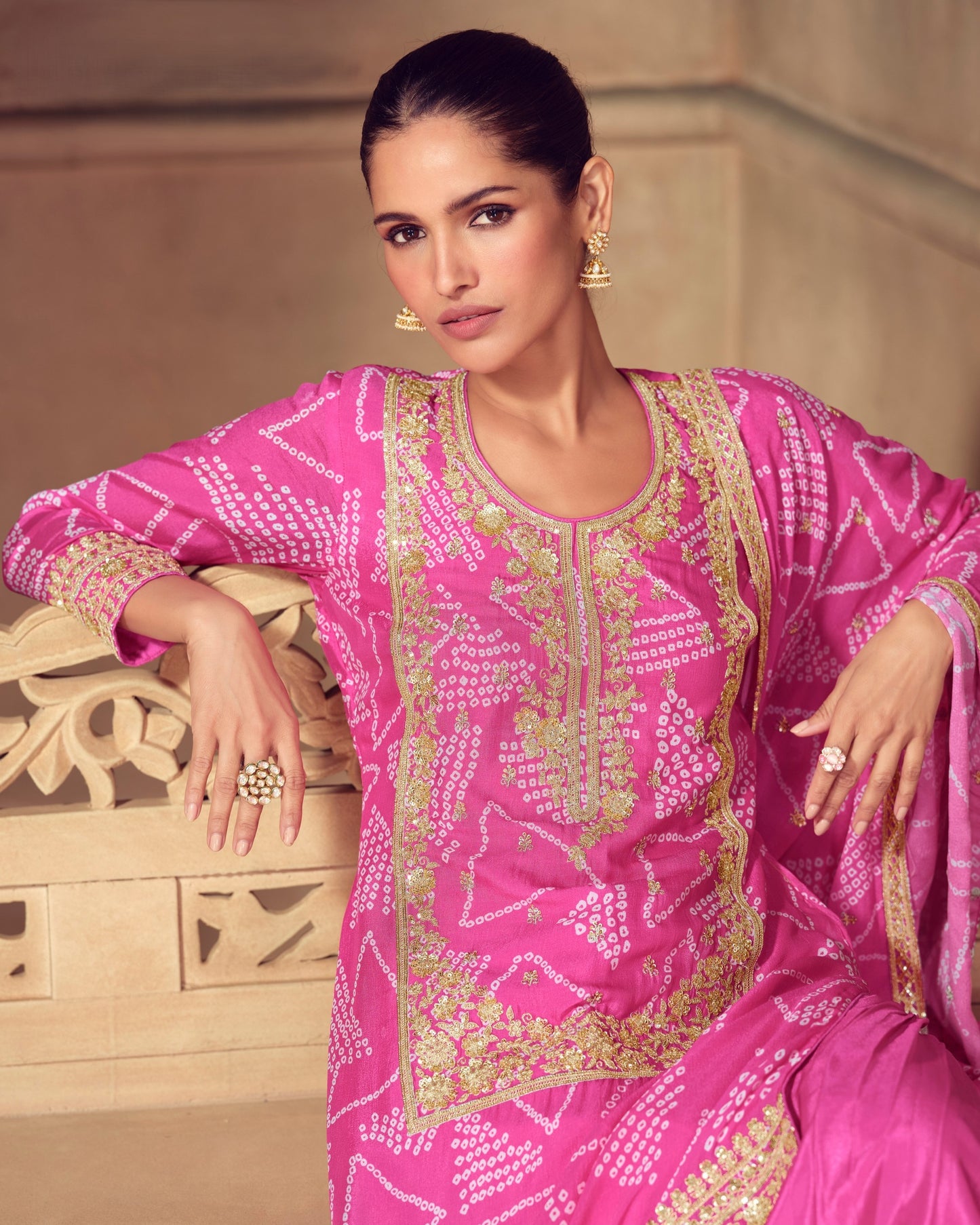Woman wearing a pink embroidered traditional outfit with gold details.