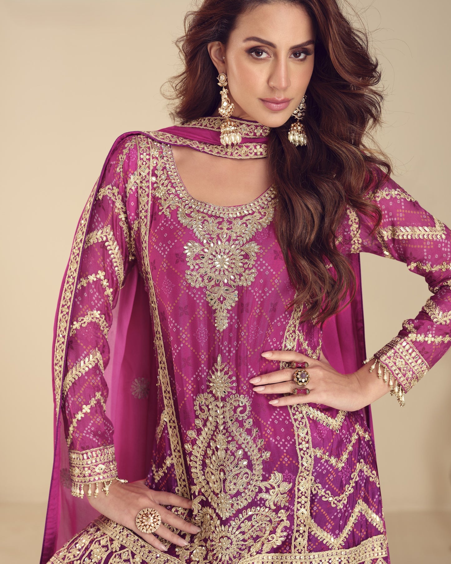 Woman wearing a purple embroidered traditional outfit with gold details on a beige background