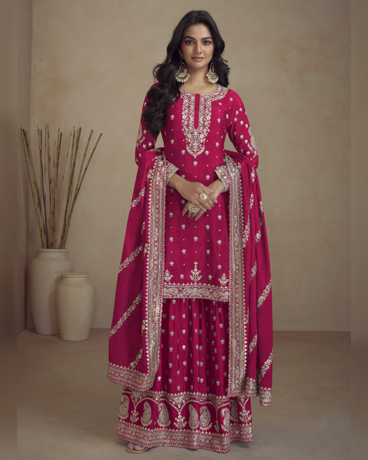 Woman wearing a pink traditional outfit with white embroidery against a beige background