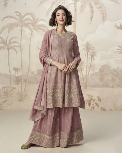 Woman wearing a traditional pink outfit with gold patterns against a scenic backdrop