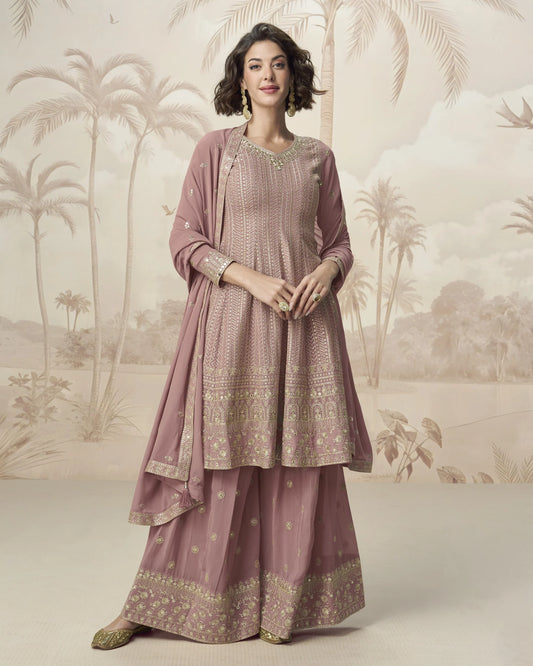 Woman wearing a traditional pink outfit with gold patterns against a scenic backdrop