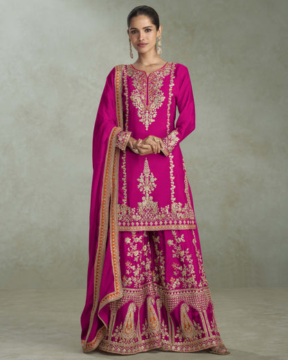 Woman wearing a pink embroidered traditional outfit with a plain background