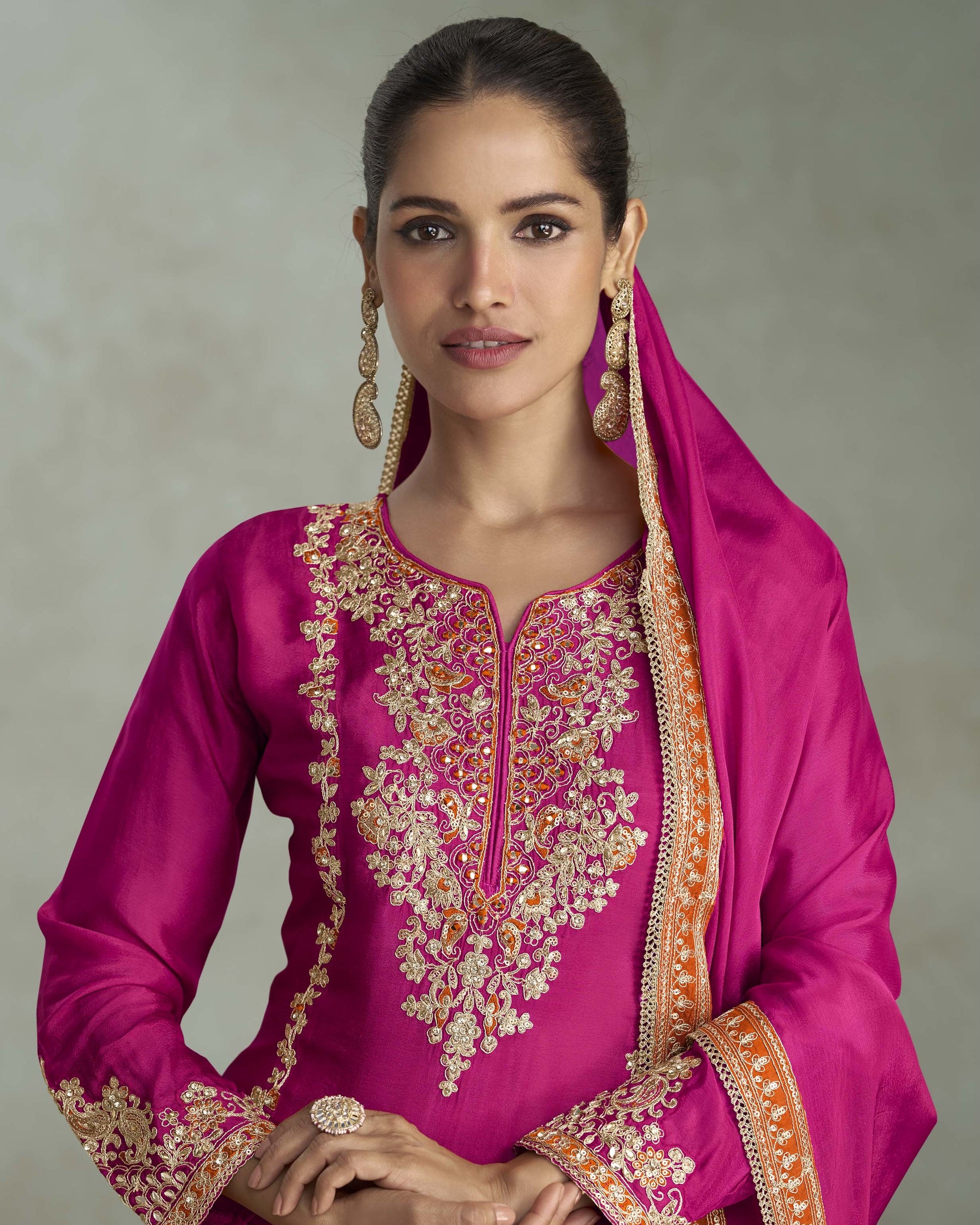 Woman wearing a pink embroidered traditional outfit with a neutral background
