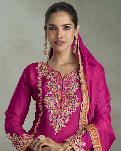 Woman wearing a pink embroidered traditional outfit with a neutral background