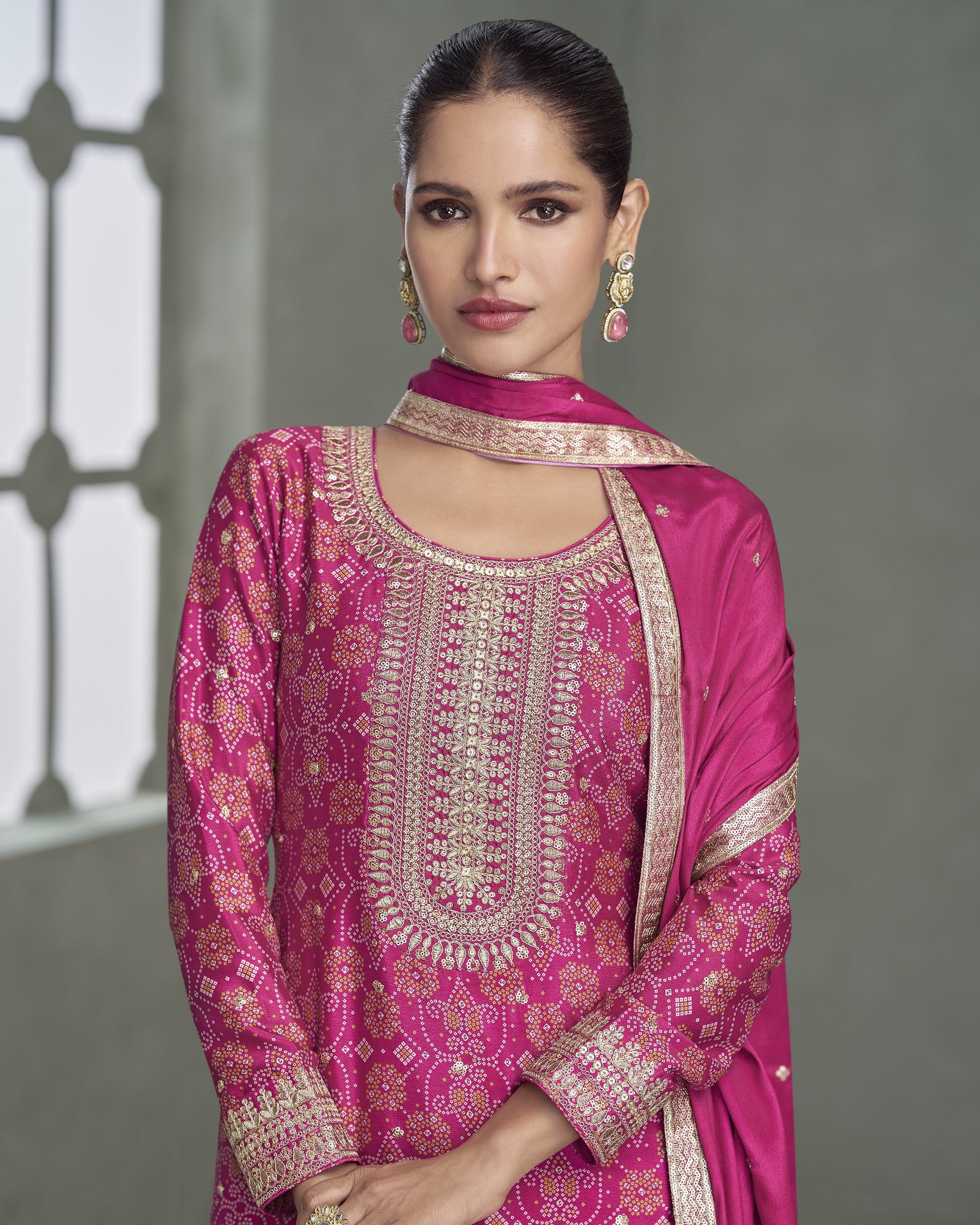 Woman wearing a pink embroidered traditional outfit with a gray background