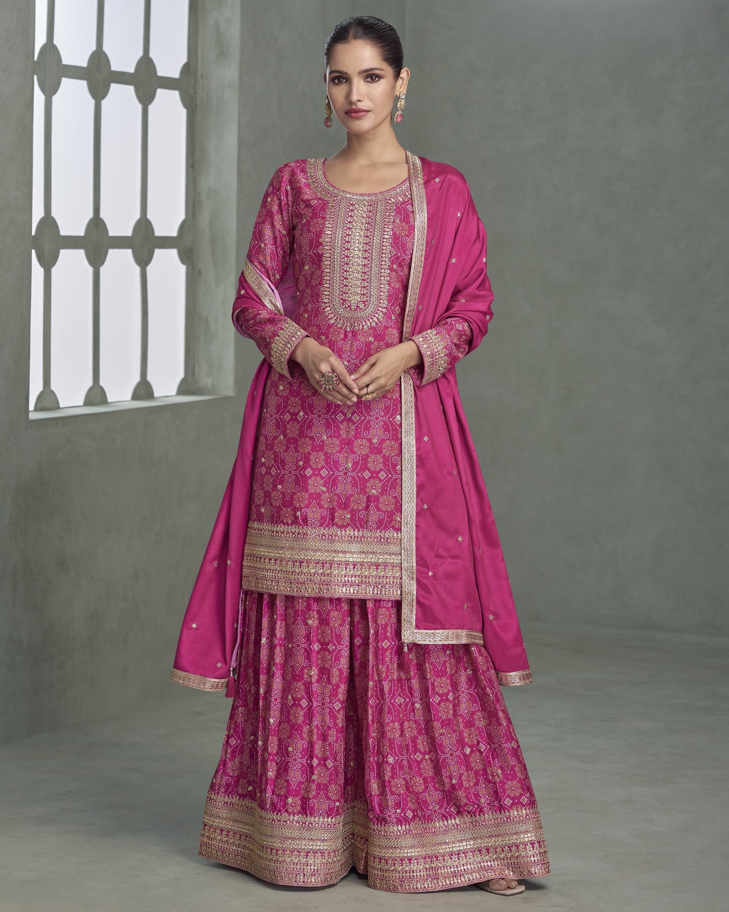 Woman wearing a pink traditional outfit with intricate patterns against a gray background