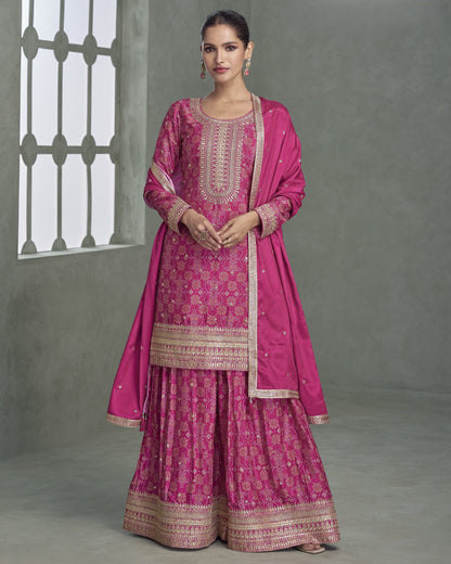 Woman wearing a pink traditional outfit with intricate patterns against a gray background