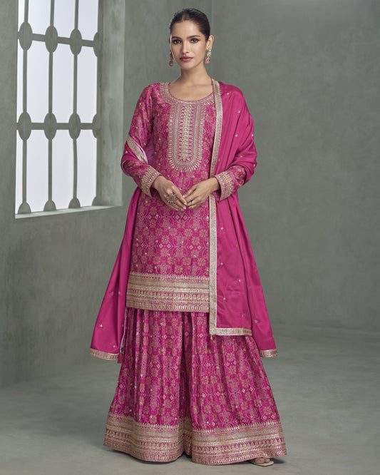 Woman wearing a pink traditional outfit with intricate patterns against a gray background